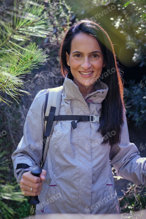 Preview: Happy woman with trekking sticks in forest