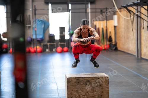 Preview: Strong mature woman exercising with a box in a gym