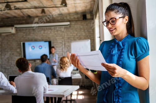 Preview: Smiling confident successful business woman leader standing in an office at team meeting.