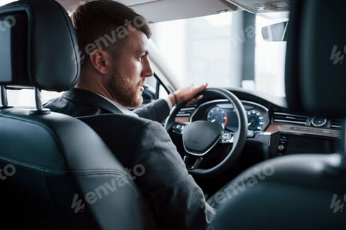 Preview: Elegance and beauty. Modern businessman trying his new car in the automobile salon