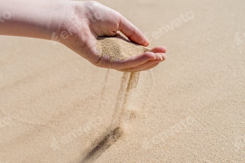 Preview: A hand pouring sand on a desert sand dune. Sand slips sifting through fingers
