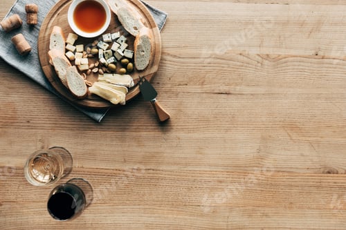 Preview: top view of wine glasses, food and corks on wooden surface