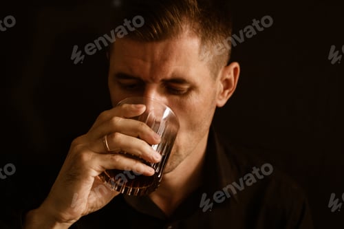 Preview: young man drinking whiskey from a glass