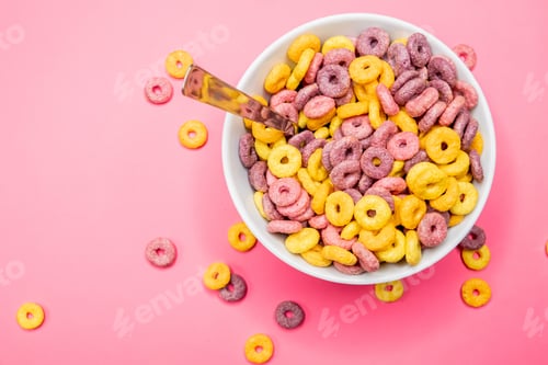 Preview: Top view of a bowl of cereal with a spoon on a pink surface under the lights