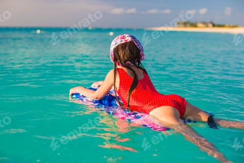 Preview: Little adorable girl on a surfboard in the turquoise sea