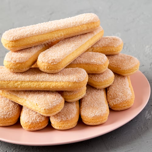 Preview: Savoiardi or ladyfingers cookies on a pink plate over gray background, side view. Close-up.