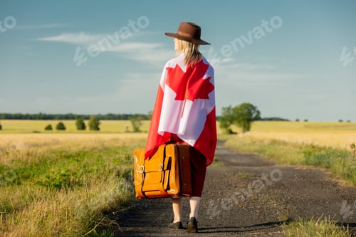 Preview: Girl in Canada flag with suitcase on country road in sunset