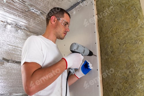 Preview: Worker in goggles with screwdriver working on insulation.