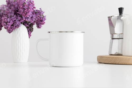 Preview: Enamel mug mockup with a moka pot and a bouquet of lilac in a vase on a white table.