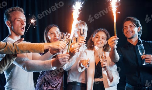 Visualização: Grupo de amigos alegres comemorando o ano novo em ambientes fechados com bebidas nas mãos