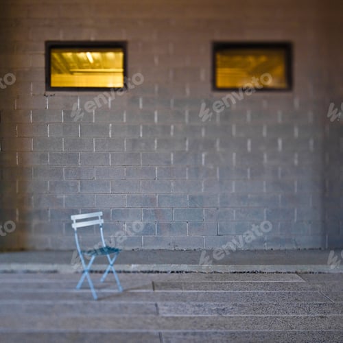 Preview: Folding chair in front of concrete block wall.