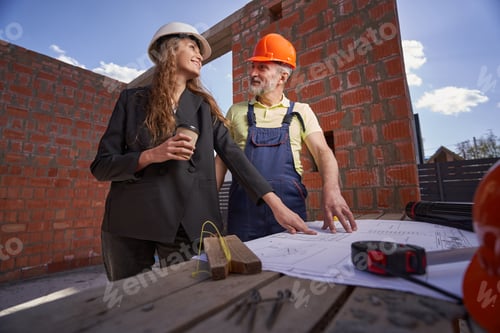 Preview: Pleased builder and woman site engineer checking drawings