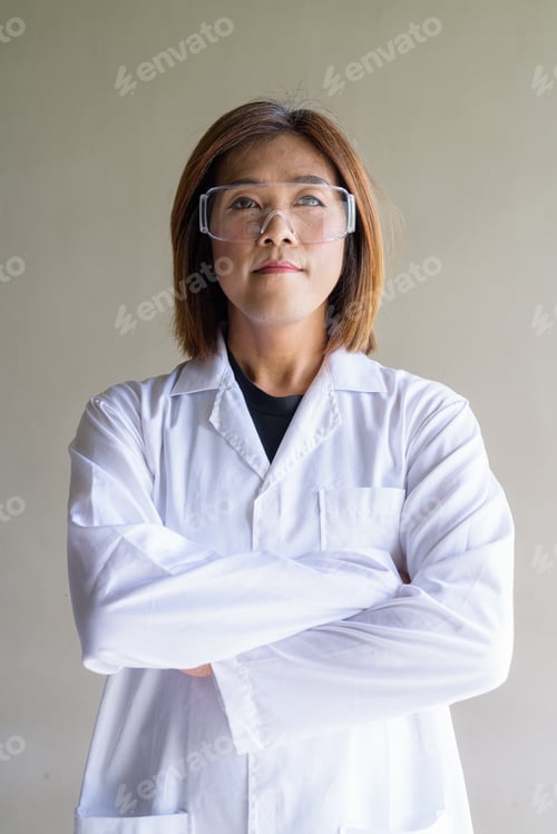Preview: Confident transgender non-binary person in lab coat and protective glasses