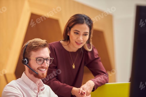 Preview: Businessman Wearing Headset Talking To Colleague In Busy Customer Services Centre