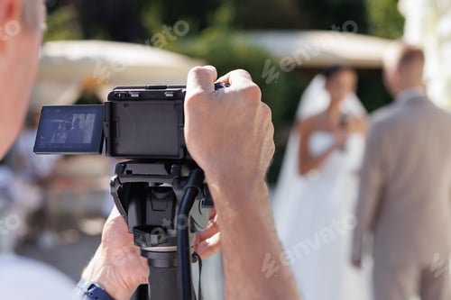 Preview: A cameraman filming a wedding ceremony with a camera on a tripod.