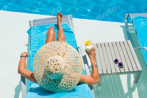 Preview: Pretty blond woman enjoying a cocktail at the pool