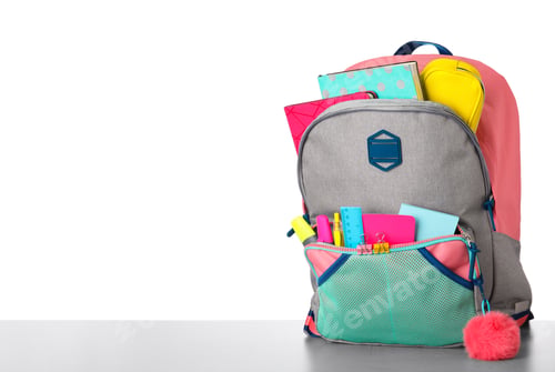 Preview: Bright backpack with school stationery on grey stone table against white background