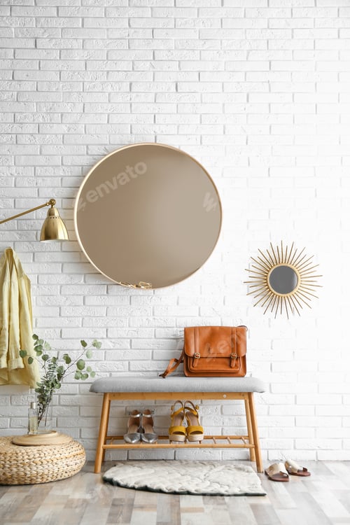 Preview: Hallway interior with big round mirror and shoe storage bench near brick wall