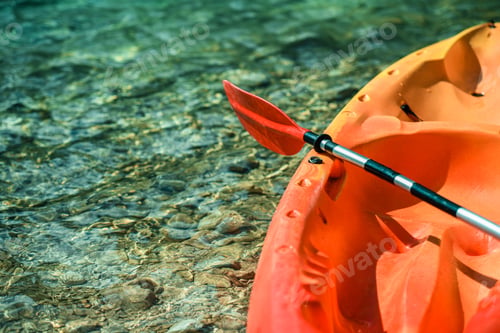 Preview: Bright Orange Kayak With Paddle Resting on Clear Water Surface