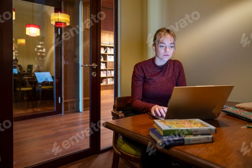 Preview: Young woman focusing on work at her laptop in a cozy home office.