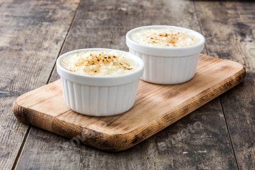 Preview: Delicious creamy rice pudding topped with cinnamon resting on wooden board