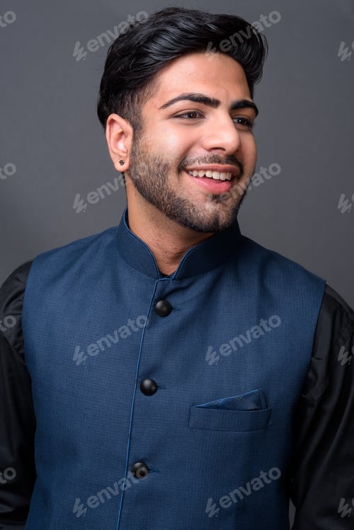 Preview: Young handsome Indian businessman against gray background
