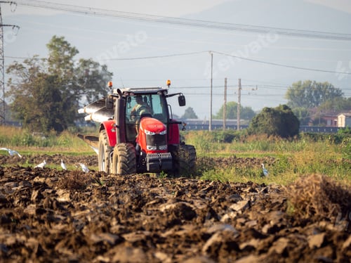 Preview: Farmer driving tractor plowing land at the end of the summer season