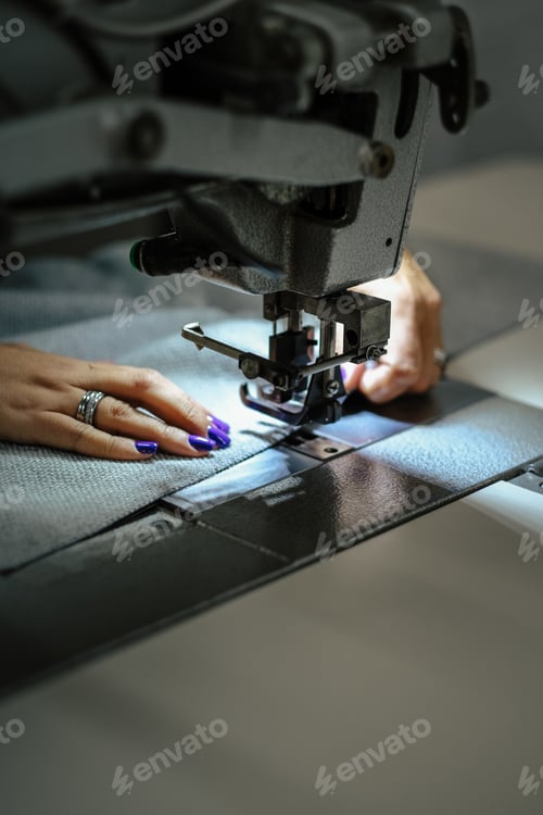 Preview: Vertical shot of female hands using a sewing machine
