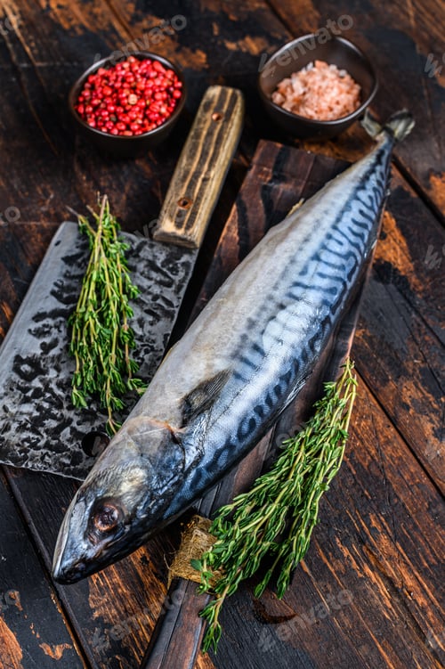 Preview: Fresh Raw fish Mackerel on a wooden cutting board with a cleaver. Dark wooden background. Top view