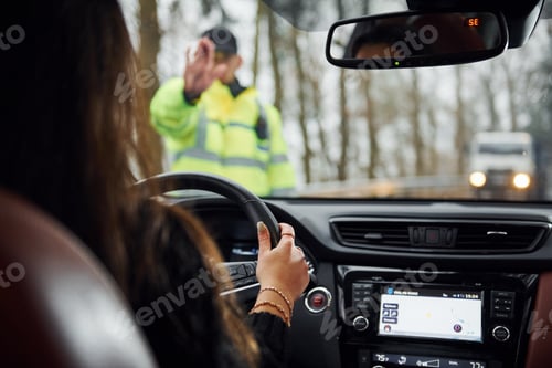 Preview: Male police officer in green uniform stops vehicle with female driver on the road