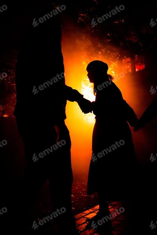 Preview: Silhouetted individuals standing in front of a bright light source in a forest