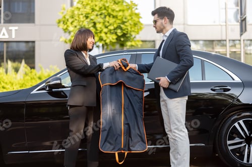 Preview: Female chauffeur gives a businessman his suit, after a business trip by car