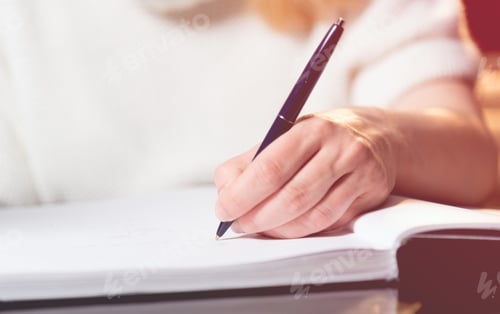 Preview: Woman writing into a notebook with a pen