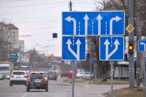 Preview: Traffic sign pointing multiple road lanes direction on city street.
