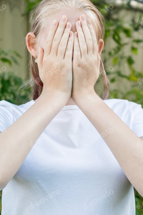 Preview: Girl wearing white mockup t-shirt covering her face with hands
