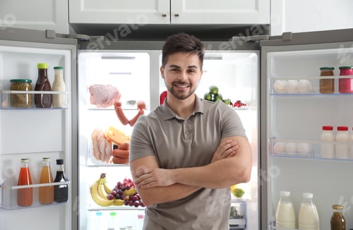 Preview: Young man near open refrigerator in kitchen