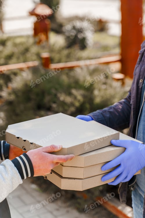 Preview: Vertical photo: 4 pizza boxes. Courier in gloves. Customer receives 2+2 pizza safely.