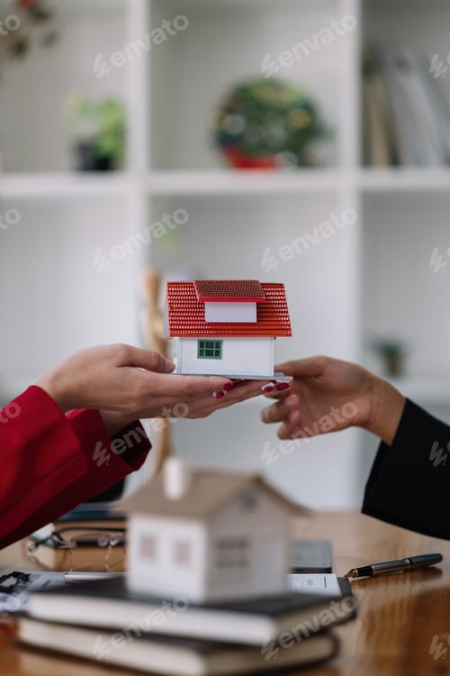 Preview: Real estate agent sales manager holding house model to customer after signing rental lease contract
