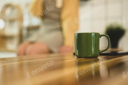 Preview: A green coffee cup sits on a wooden countertop in kitchen