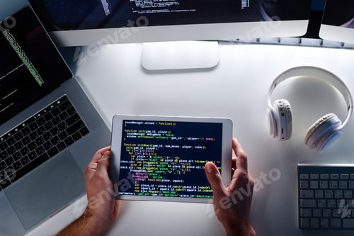 Preview: Above view of hands of male IT engineer holding tablet with coded data on screen
