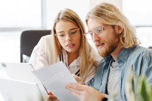 Preview: Focused young professionals reviewing documents together in modern office