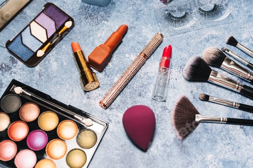 Preview: makeup brushes, decorative cosmetics, false eyelashes on a blue background. the view from the top