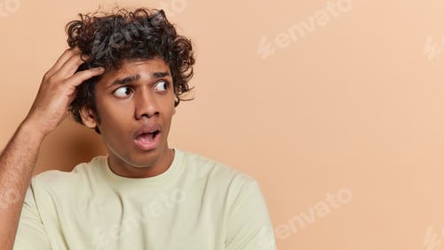 Preview: Studio shot of worried Hindu man scratches head stares impressed keeps mouth opened feels puzzled