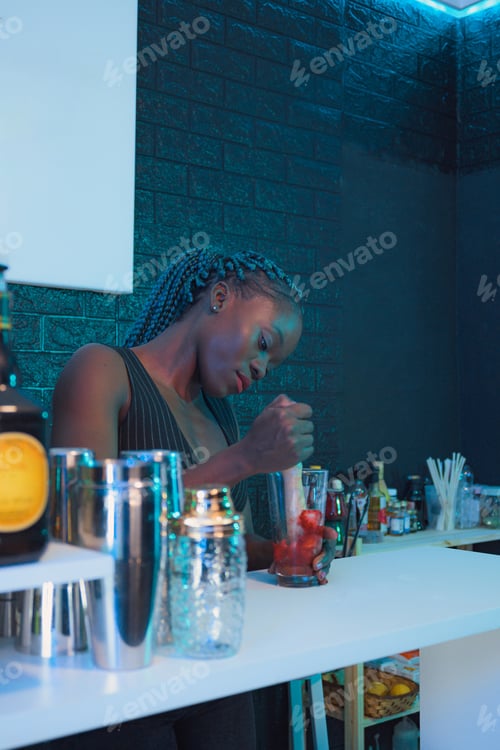 Preview: Black waitress prepares a cocktail on the bar of a pub