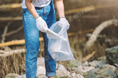 Preview: Close up on hand of volunteer holding garbage bag for cleaning park area