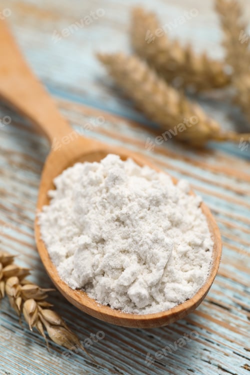 Preview: Spoon of wheat flour on light wooden table, closeup
