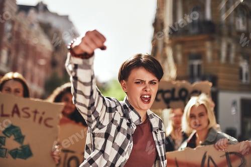 Preview: Emotional young woman screaming a slogan and leading a group of demonstrators on the road