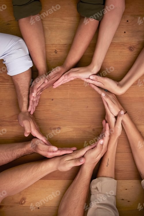 Preview: Hands, teamwork and circle with business people on a wooden table in the office closeup from above.