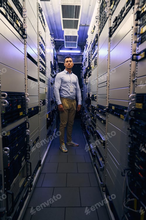 Preview: Serene IT worker standing alone among server racks