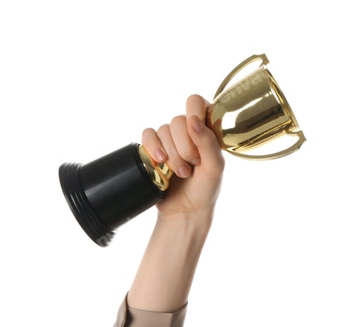 Preview: Woman with golden trophy cup on white background, closeup